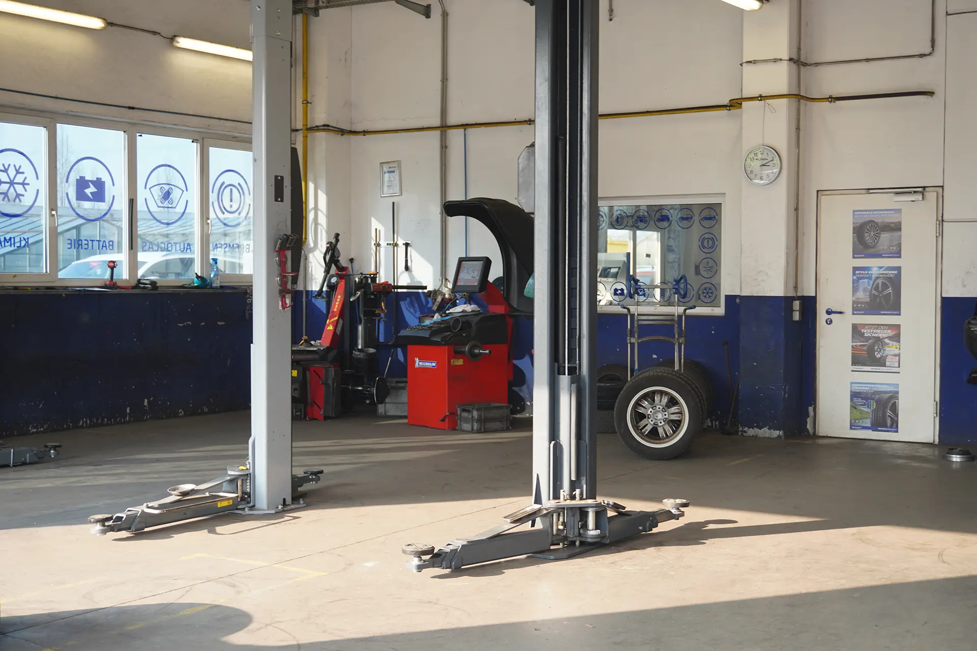 Ein Blick in eine moderne Autoreparaturwerkstatt mit einem zentralen Fahrzeuglift und Diagnosewerkzeugen.